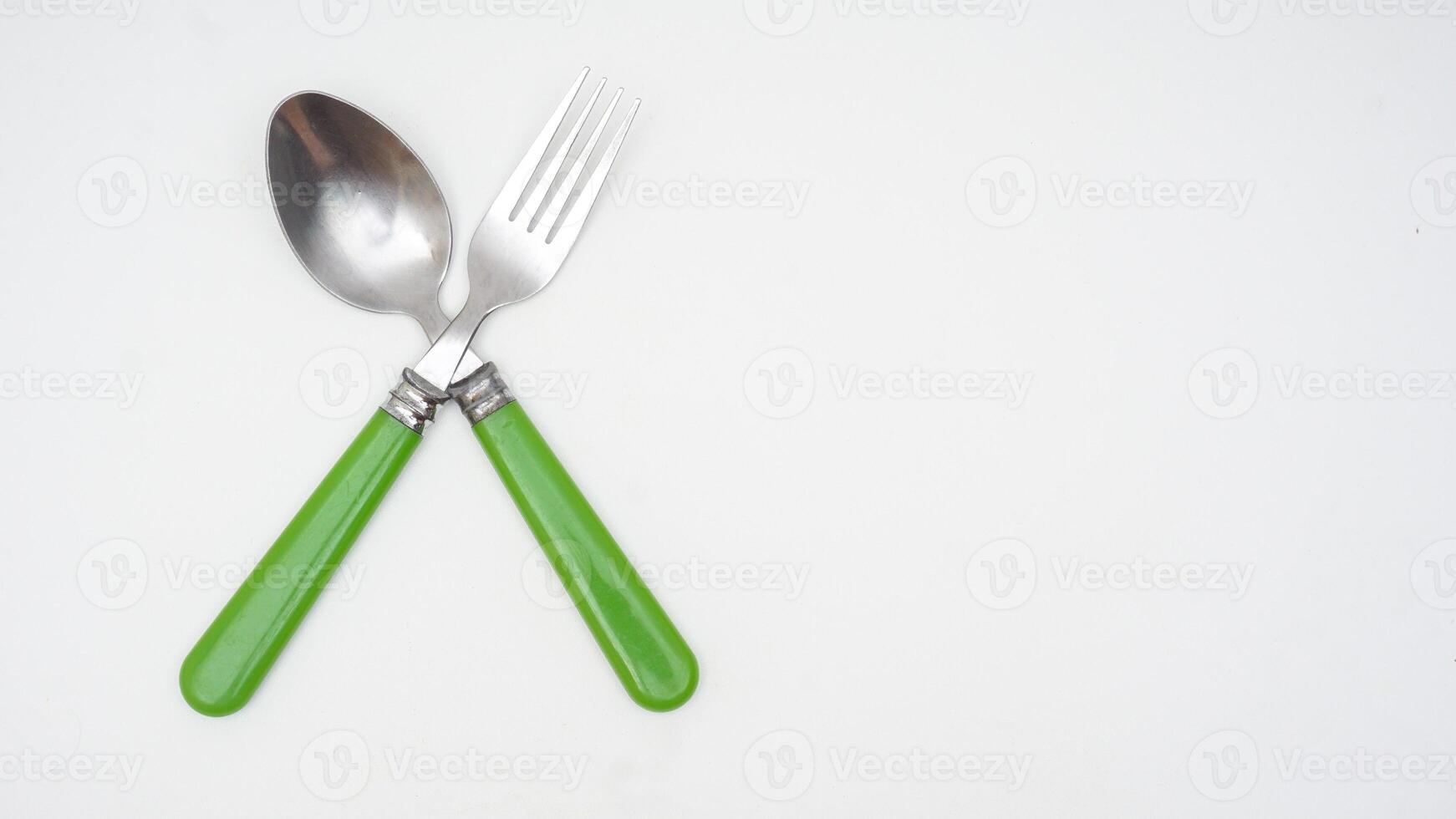 Top view of stainless steel spoon and fork with green handle isolated on white background photo
