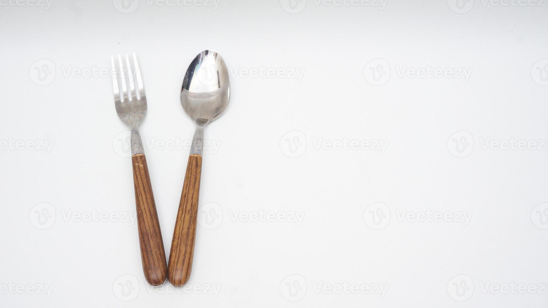 A pair of stainless steel spoon and fork with wooden handle isolated on white background photo