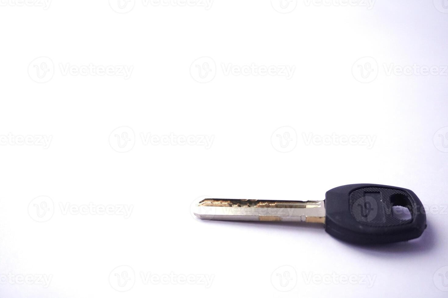 Single key lying on white surface with black plastic head photo
