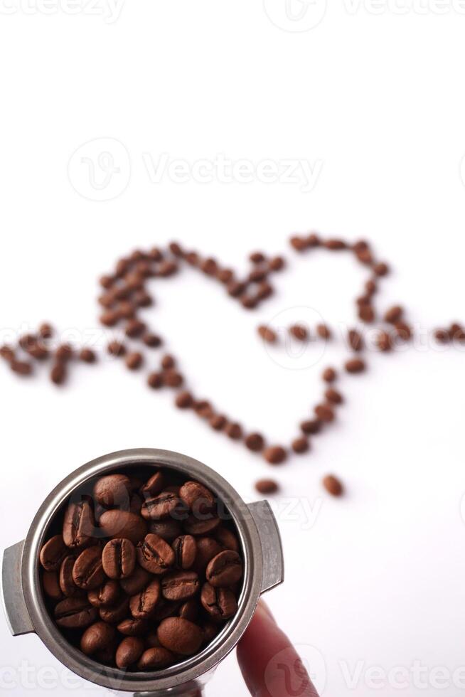 Coffee beans in portafilter with heart shape in background photo