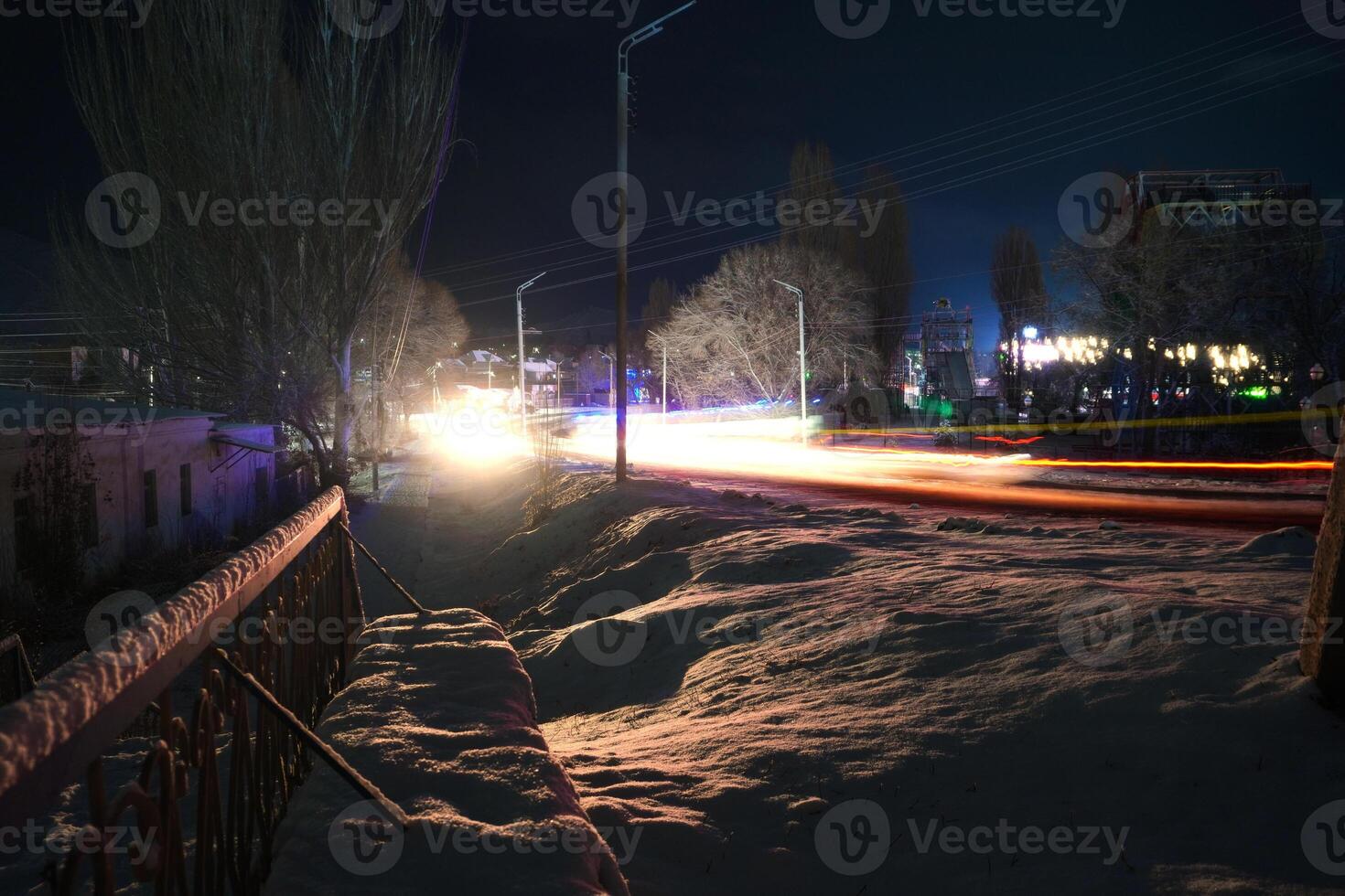 Long exposure of a snowy street at night with light trails photo