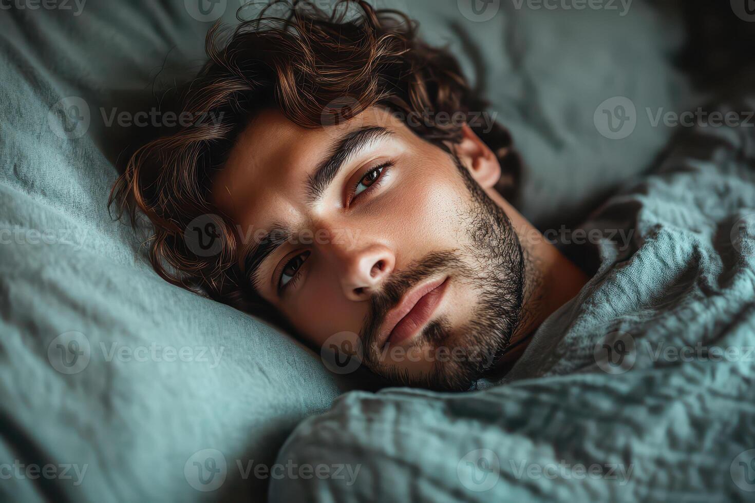 A man with curly hair laying in bed photo