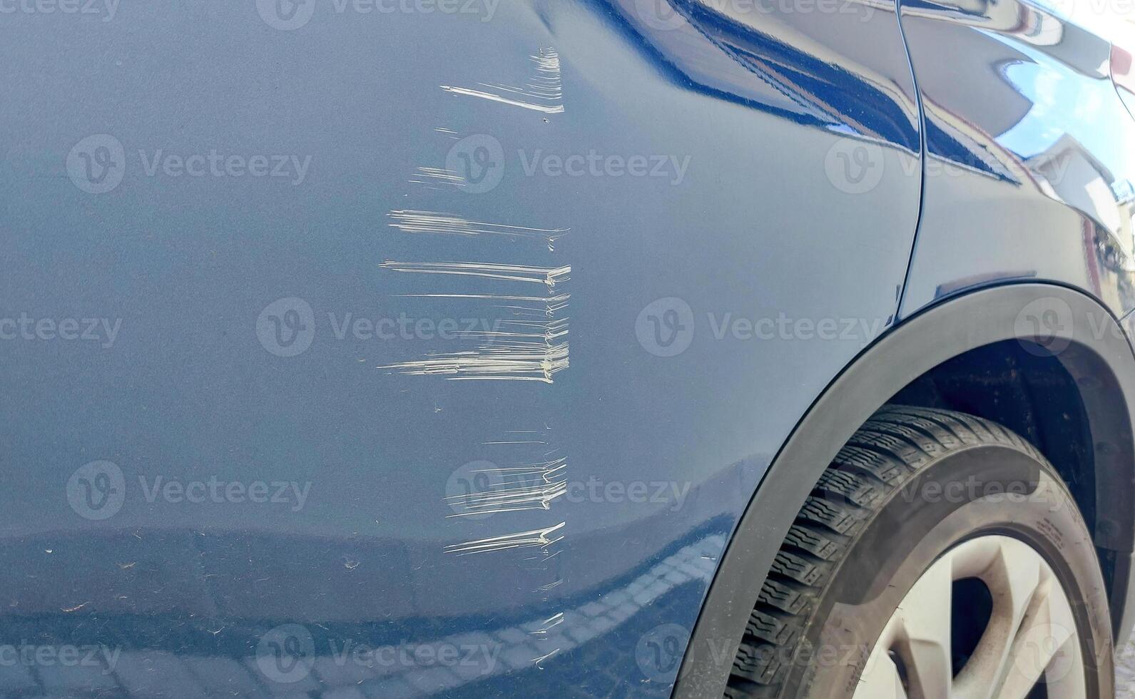 Deep scratches on a blue car door damaging the paintwork photo