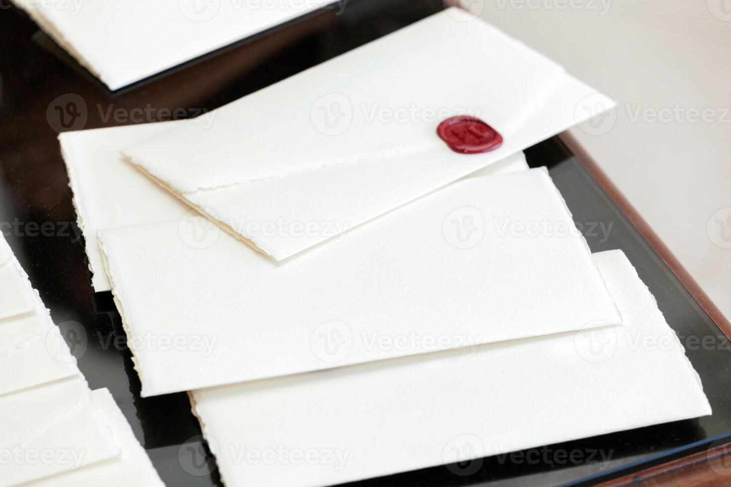 Elegant invitations with wax seal resting on dark wooden table photo