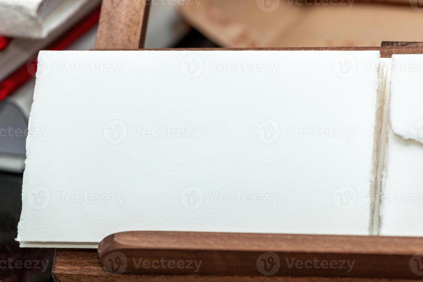 Blank handmade paper resting on wooden box with other paper sheets photo