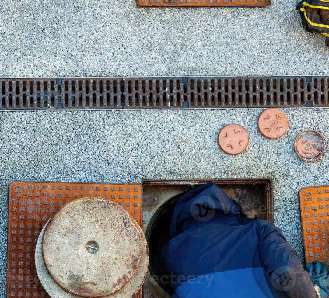 Plumber inspecting a manhole on a street photo