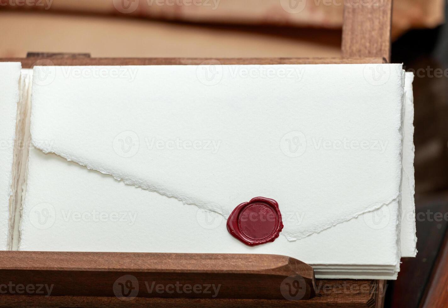 Stack of handmade paper invitations with red sealing wax in wooden box photo