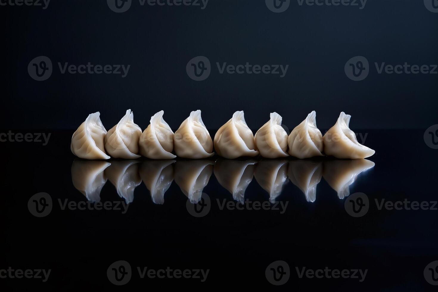 A row of meticulously crafted dumplings, glowing softly as if illuminated from within, positioned on a sleek, reflective black surface that captures their perfect reflections photo