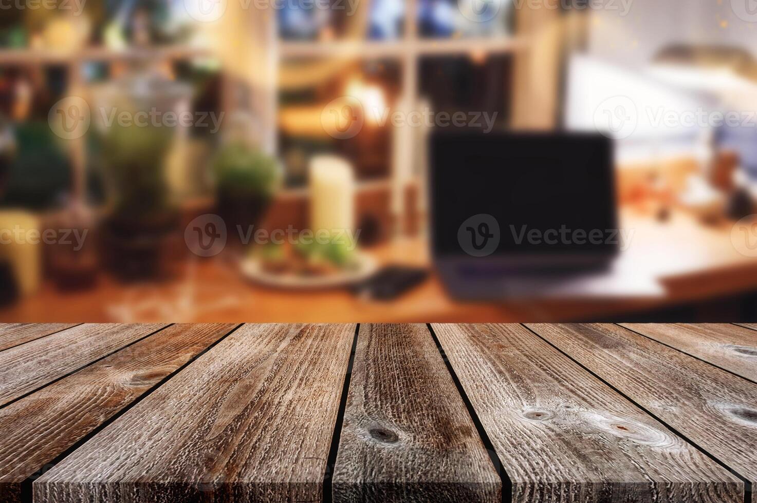 Wooden table top on blurred laptop with plant decoration and light shine photo