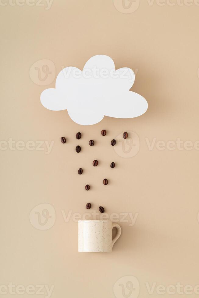 Creative layout made of cloud shape paper card note, coffee beans rain and coffee cup on beige background. Minimal concept. Trendy weather idea. Coffee aesthetic. Flat lay style. Top view banner. photo
