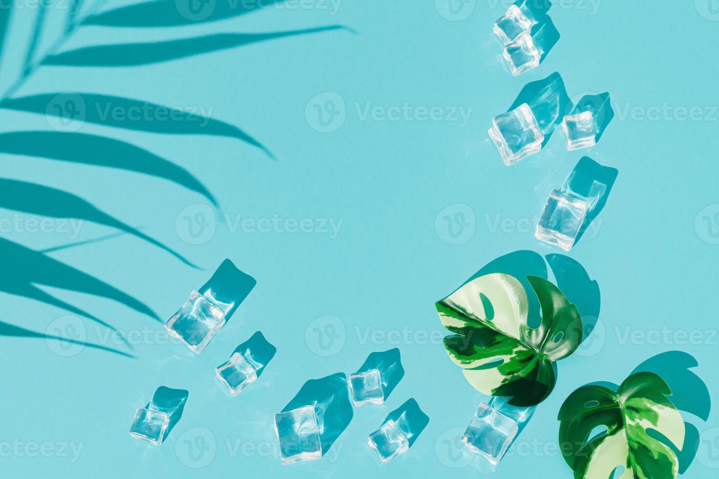 Summer day scene with ice cubes, palm leaf shadow and tropical monstera leaves on blue background. An original backdrop image with a play of light and shadow. Minimal concept. Flat lay. Copy space. photo