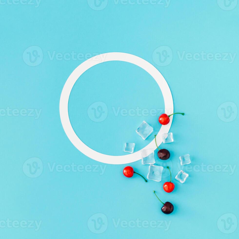 Trendy summer composition made of red cherries and ice cubes on light blue background with copy space. Flat lay summertime drink minimal concept. Cherry fruit aesthetic. Top view banner. photo
