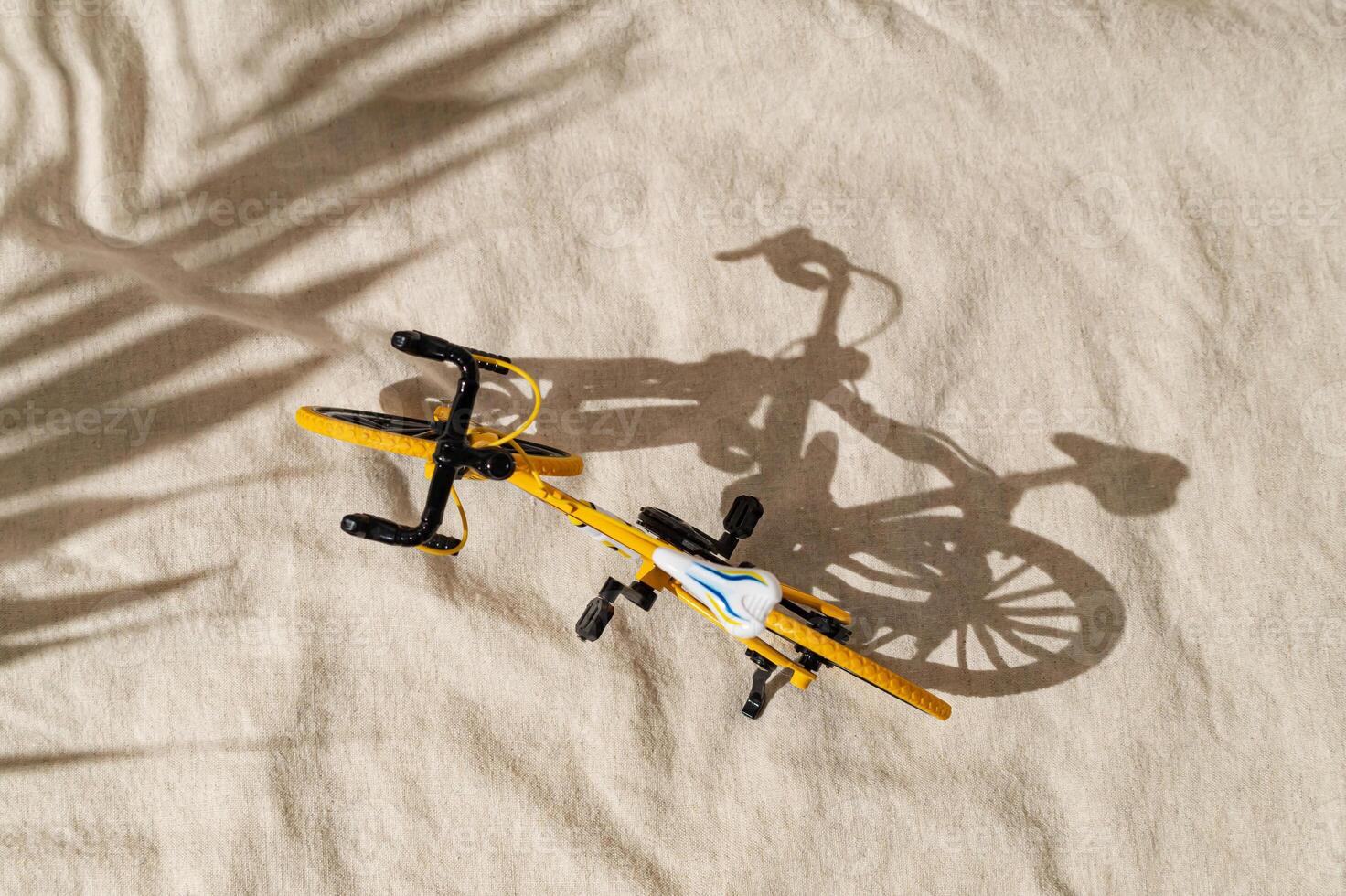 Summer day scene with yellow bicycle on sand color linen background. An original background image with a play of light and shadow. Minimal bicycling concept. Creative sport bike composition. Flat lay. photo