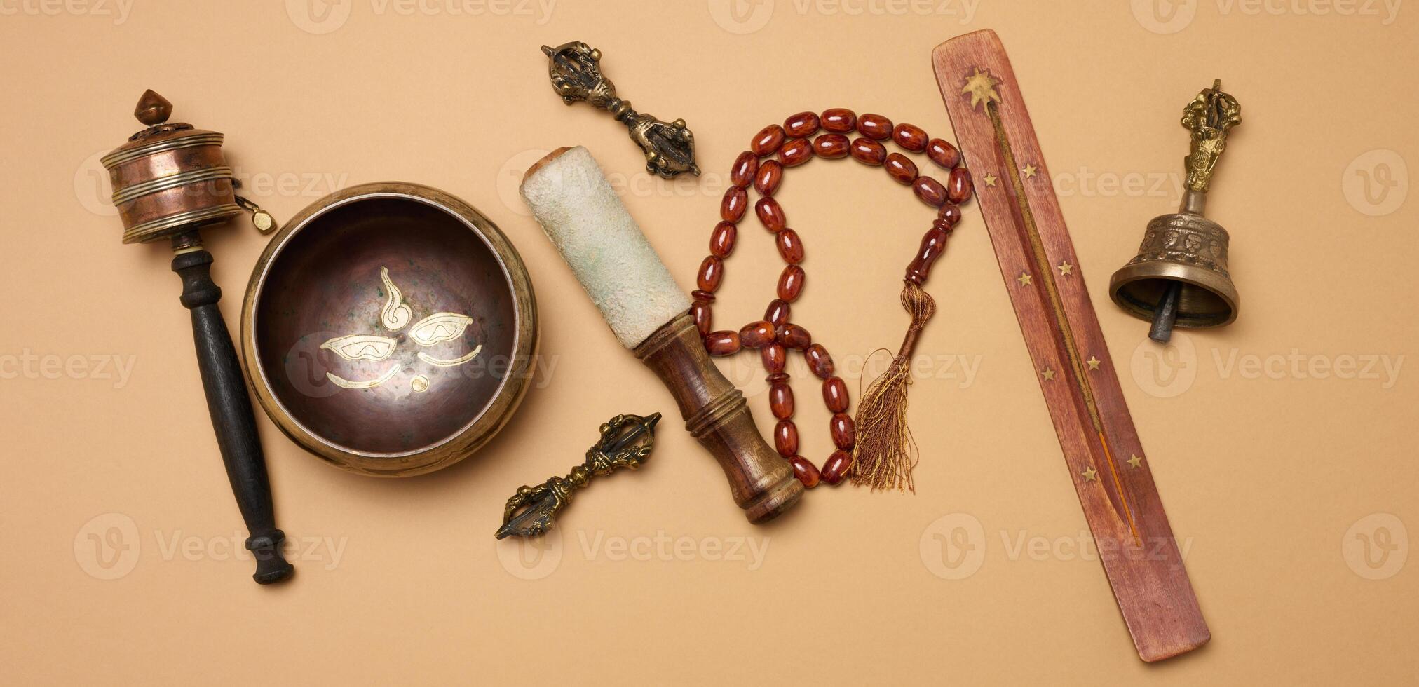Tibetan singing copper bowl with a wooden clapper on a brown background, objects for meditation and alternative medicine photo