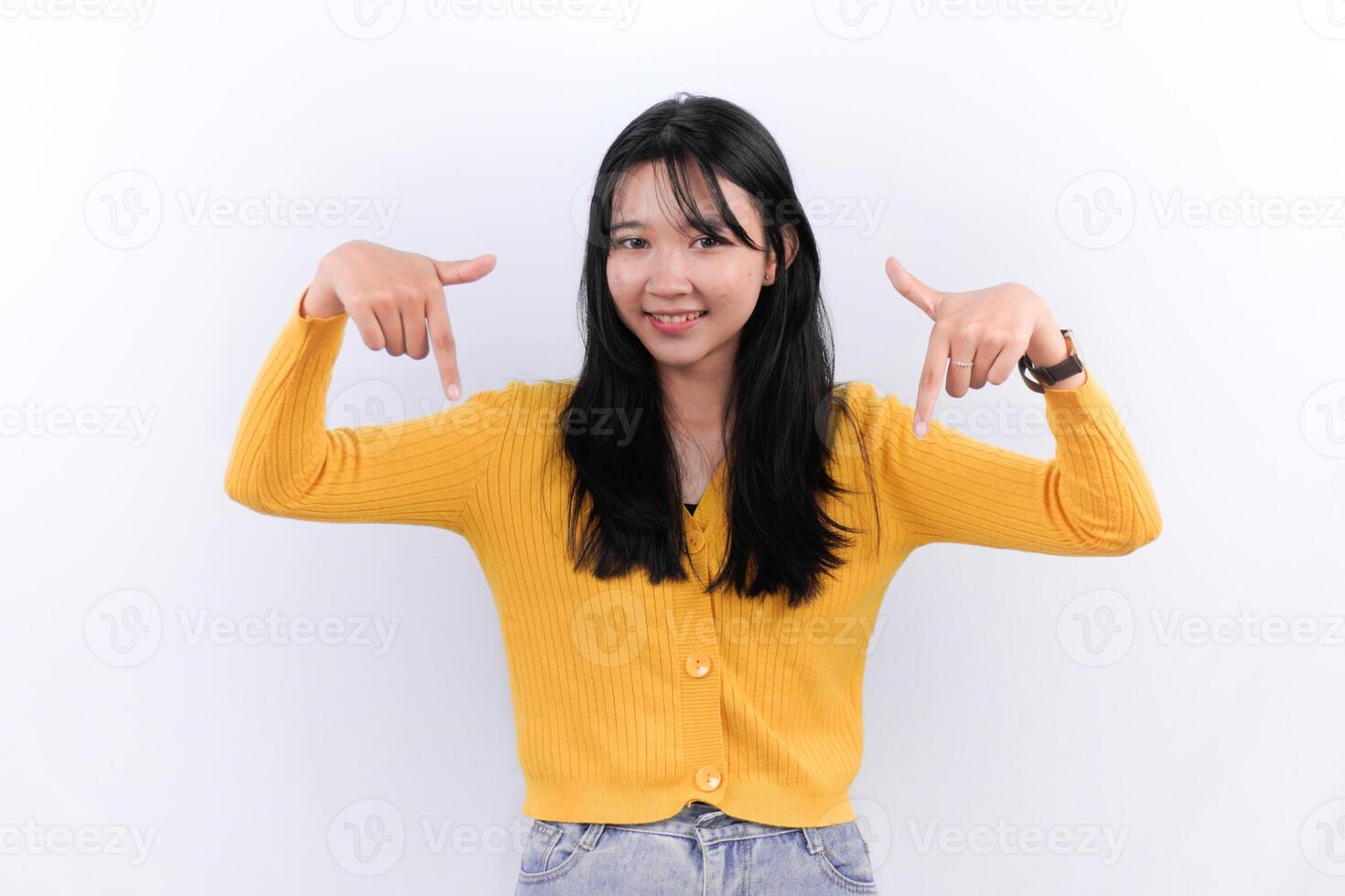 Asian woman wearing yellow shirt smiling and pointing down photo