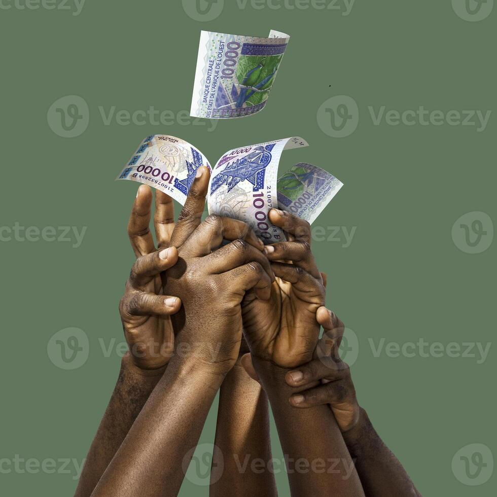 Many black African hands reaching out for West African CFA Francs notes money over green background. Stretching arms for cash. photo