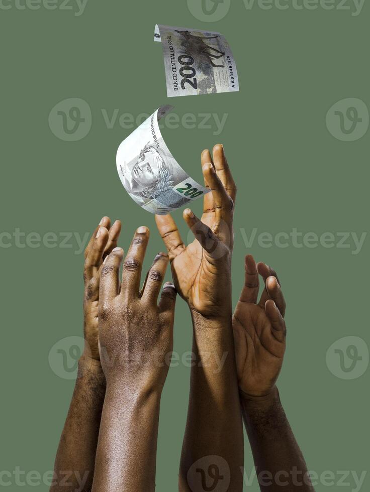 Many black African hands reaching out for Brazilian Real notes money over green background.Stretching arms for cash photo