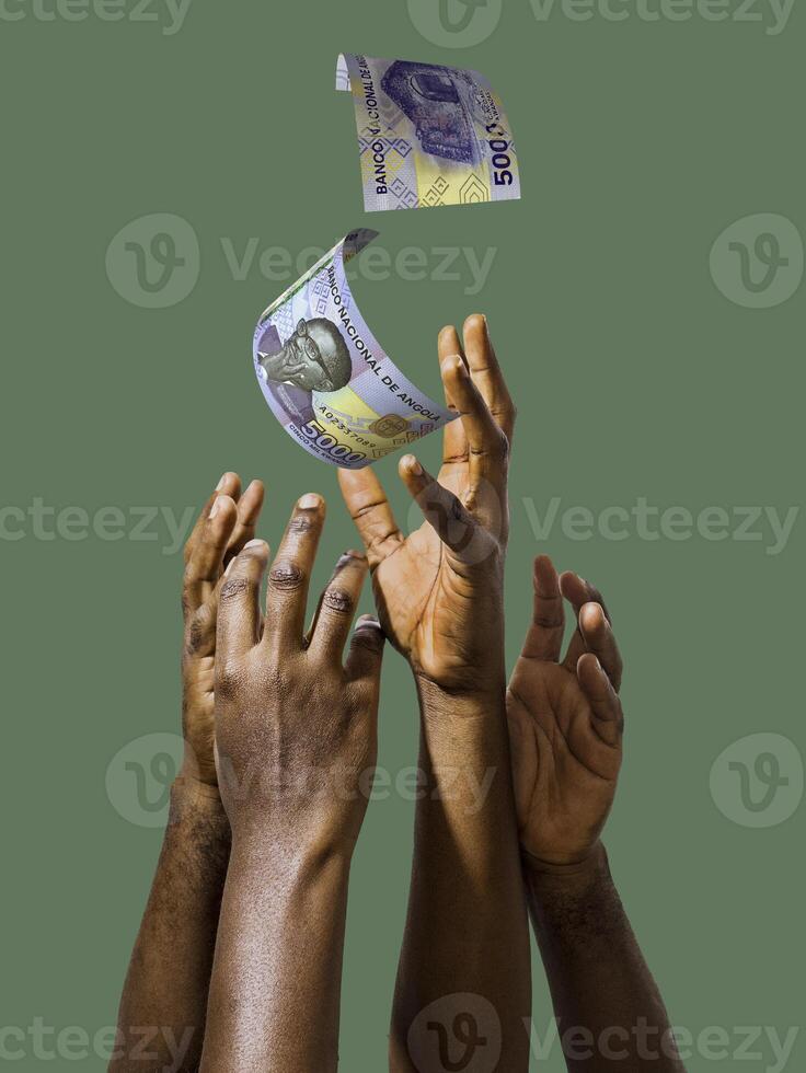 Many black African hands reaching out for Angola Kwanza notes money over green background. Stretching arms for cash. photo
