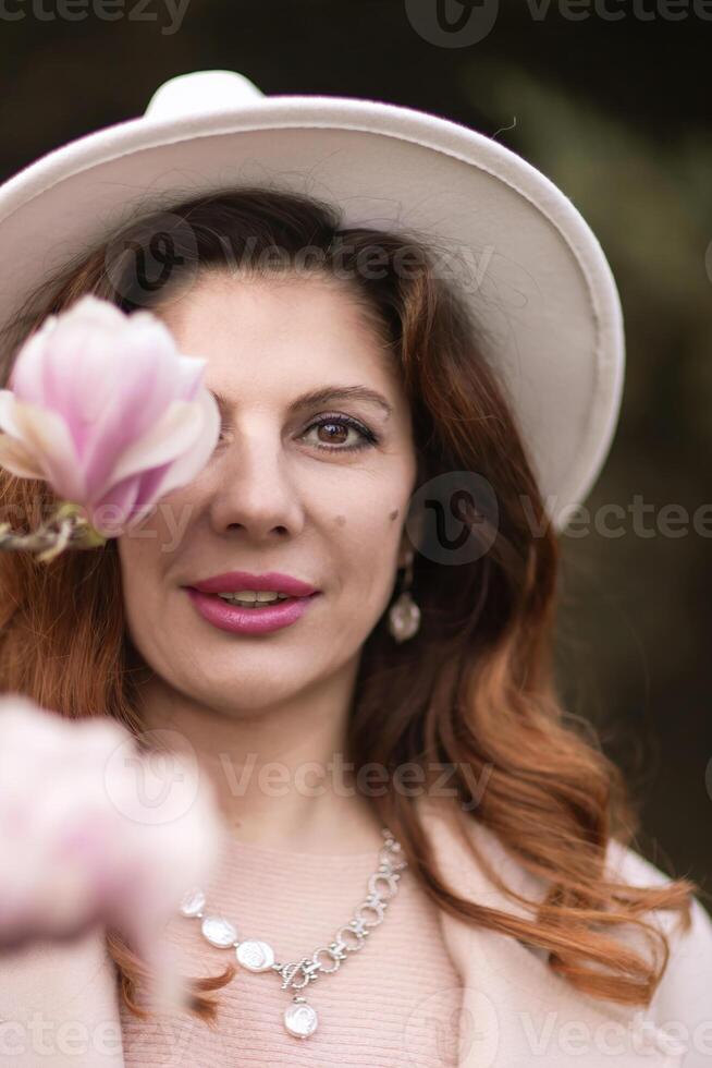 Woman holds magnolia flowers, surrounded by blossoming trees. Captured during spring, showcasing natural beauty and seasonal change. photo