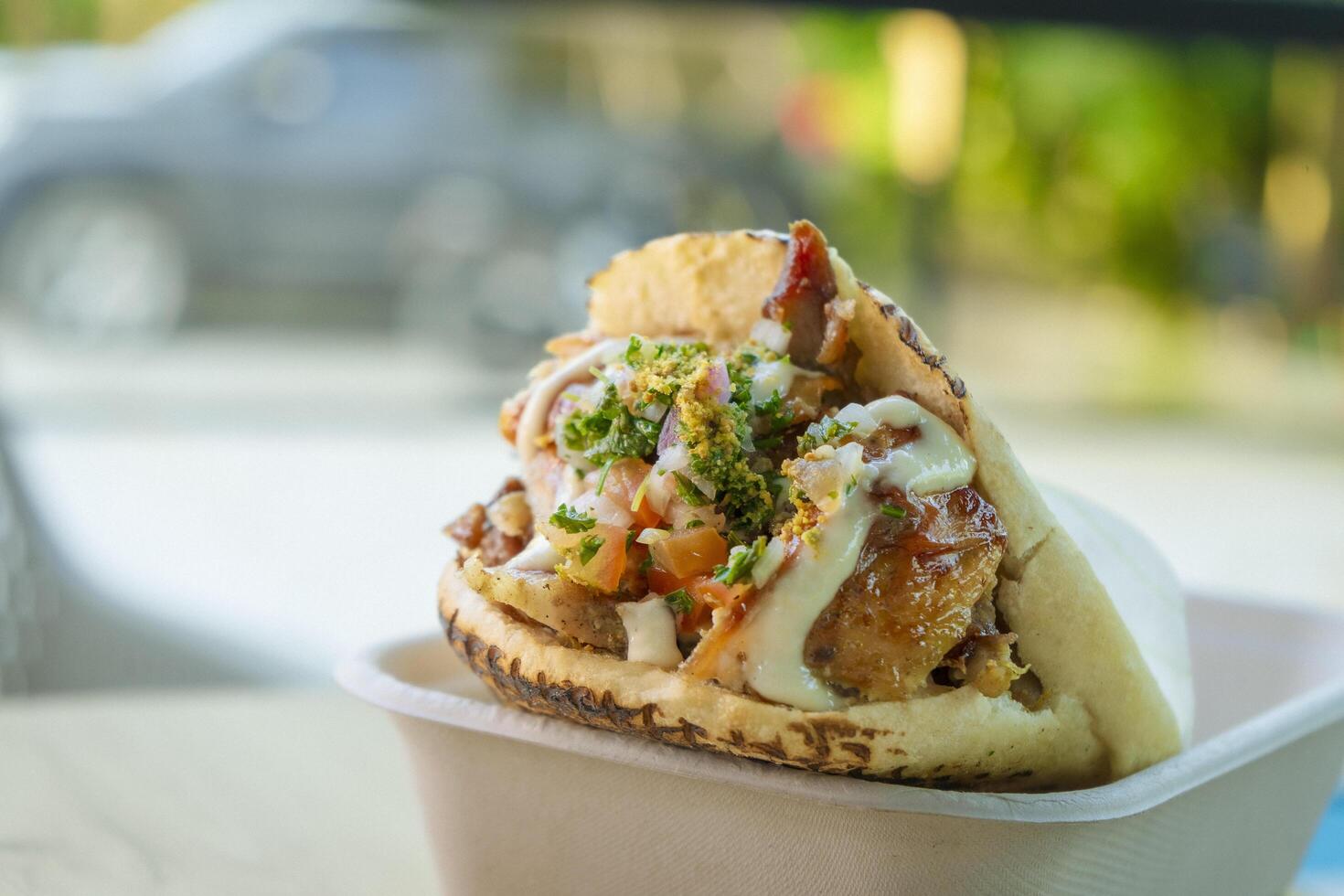 Shawarma held by a person, with sauces photo