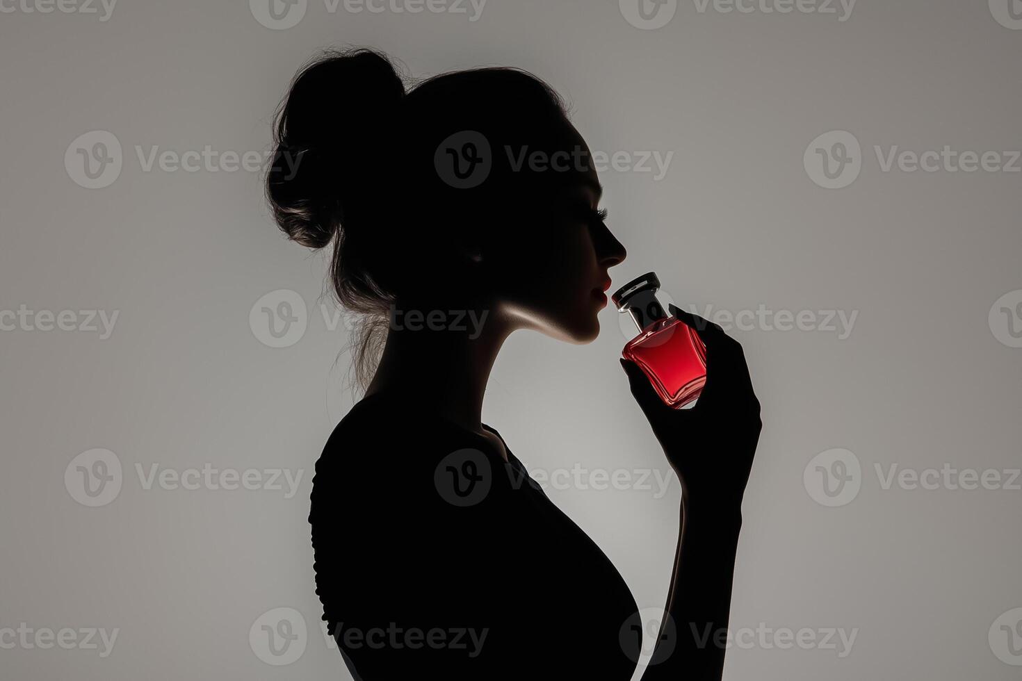 Silhouette of woman holding red perfume bottle photo