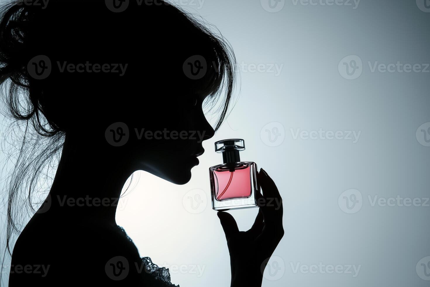 Silhouette of woman holding perfume bottle photo