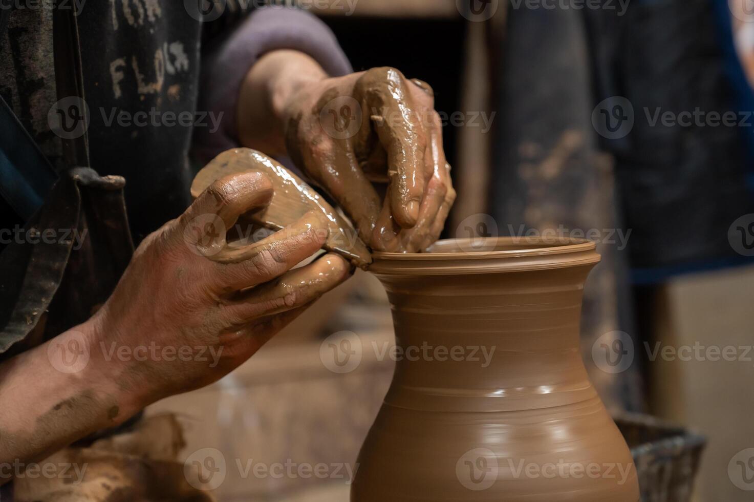 A person is making a pottery vase on a pottery wheel photo