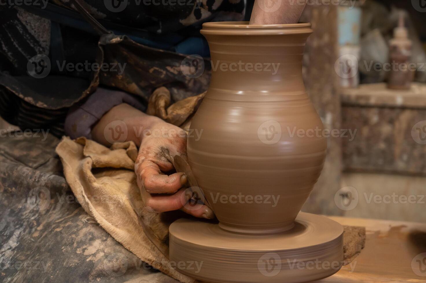 A person is making a pottery vase on a pottery wheel photo