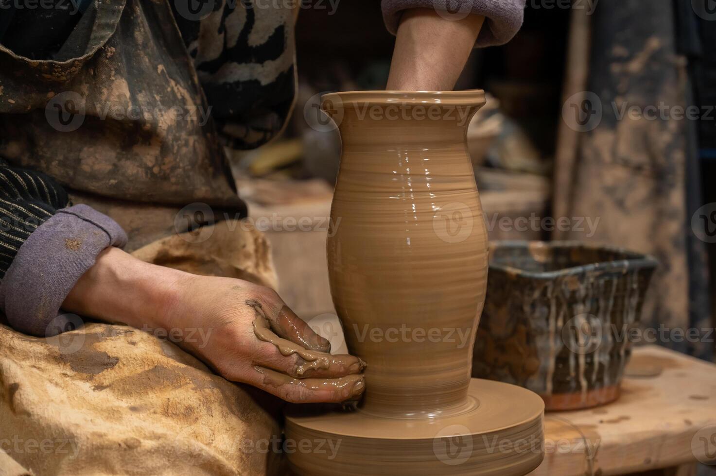A potter is making a vase on a potter wheel photo
