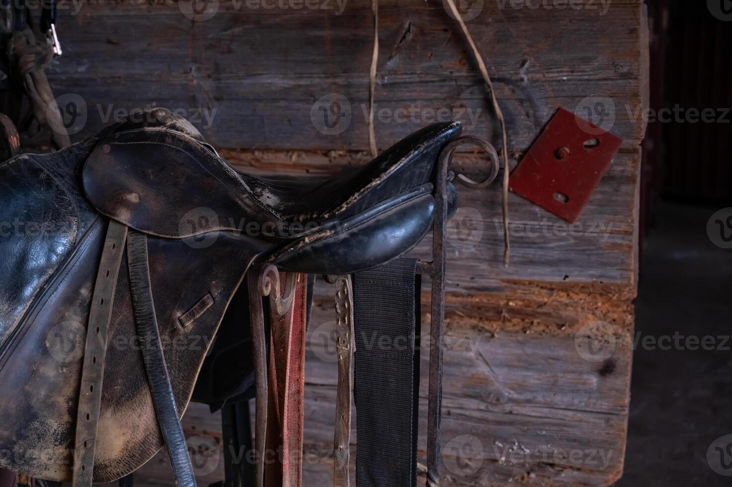 A horse's saddle is hanging on a wall photo