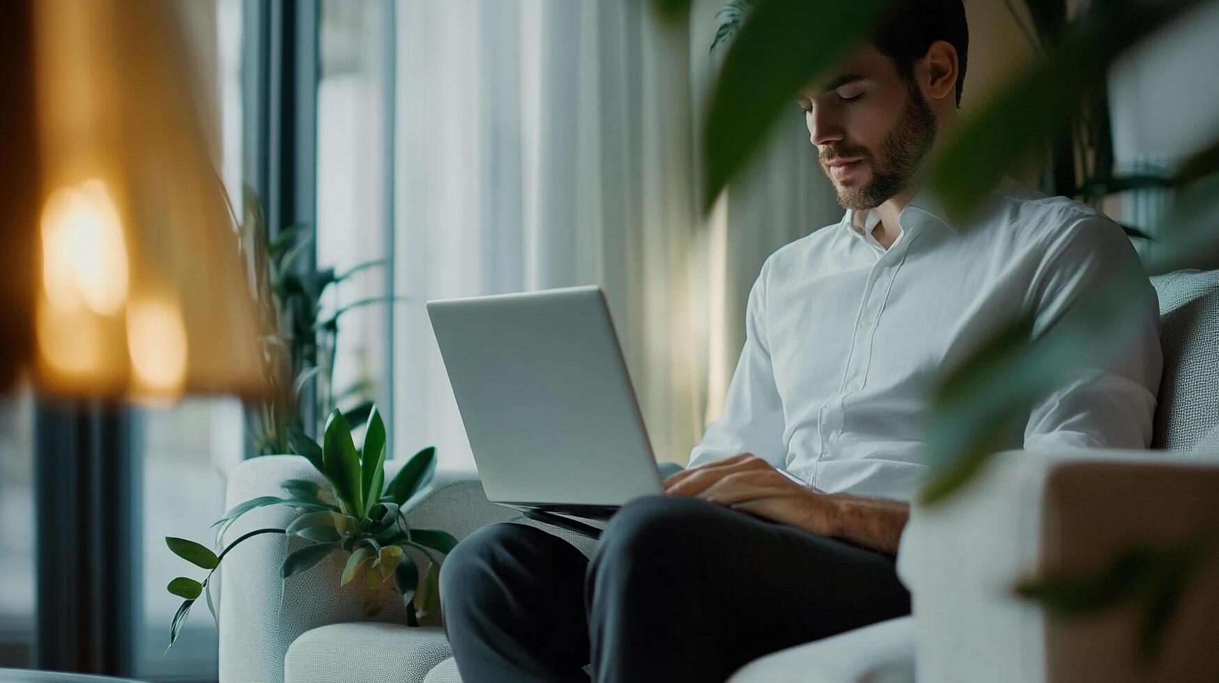 Focused individual working on a laptop in a cozy living room, bathed in soft, natural light, creating a peaceful and productive atmosphere. photo