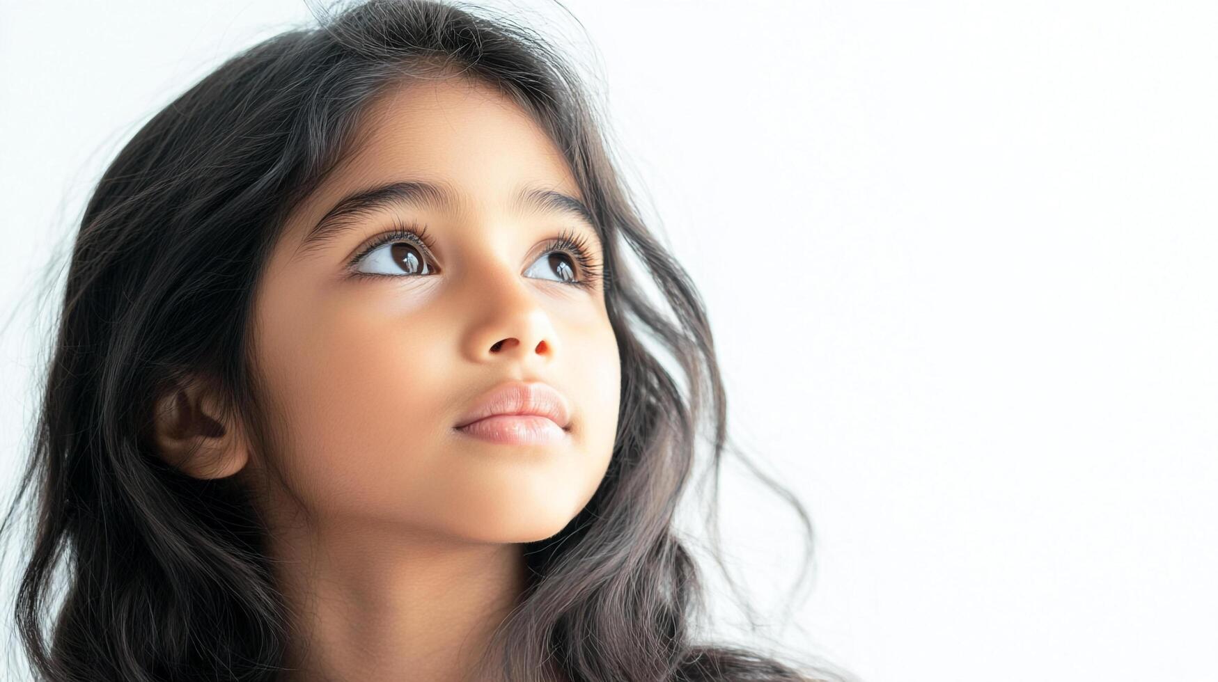 Young girl gazing upwards with a thoughtful expression. She seems hopeful and optimistic as she looks above the viewer. photo