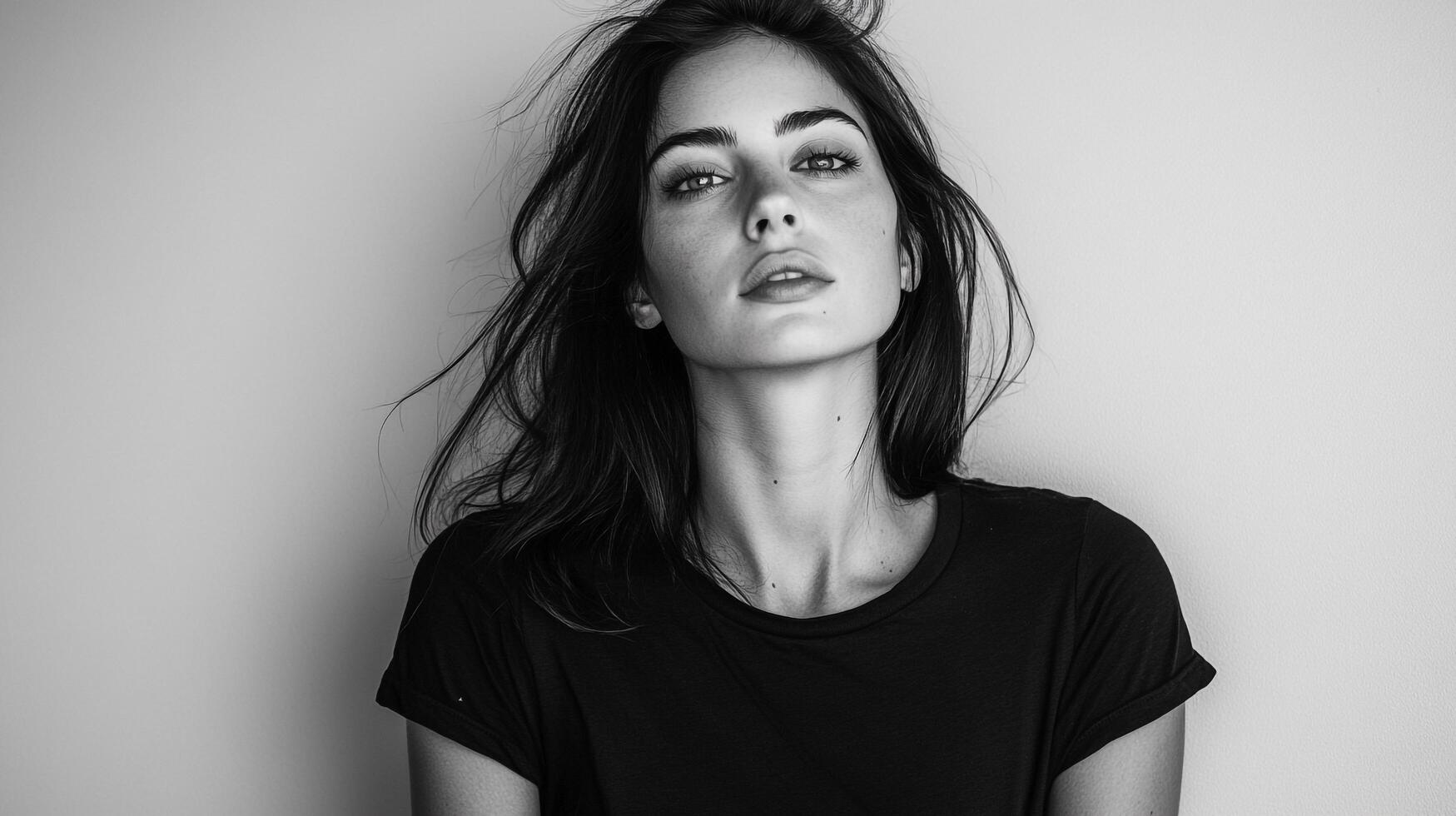 Striking monochrome portrait of a beautiful woman with dark hair and captivating eyes, set against a clean, neutral background. photo