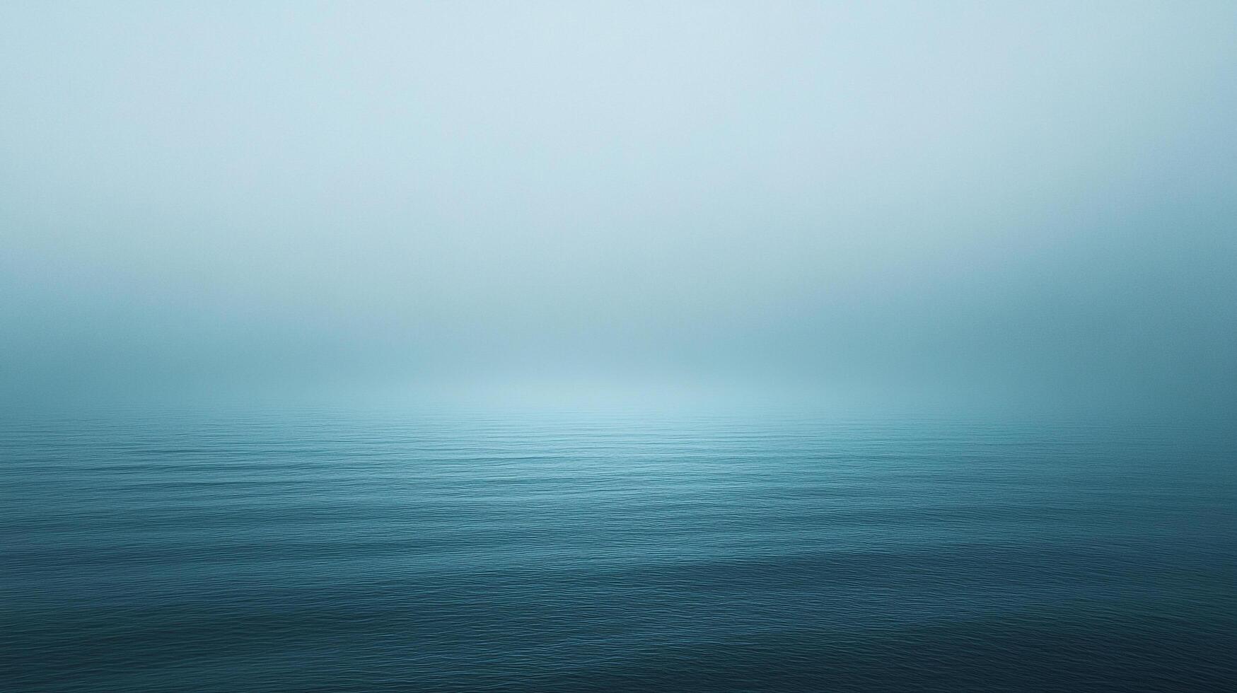 A serene expanse of water meets a hazy sky, where the horizon blends seamlessly into a gradient of blue, evoking calmness and vastness. photo