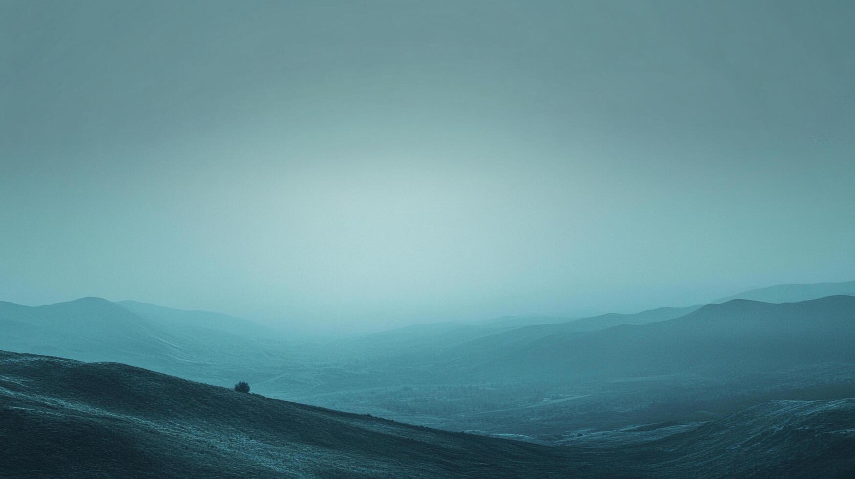 Blue-tinted mountain ranges recede into the horizon beneath a hazy sky, evoking a sense of serenity and vastness in nature's grandeur. photo