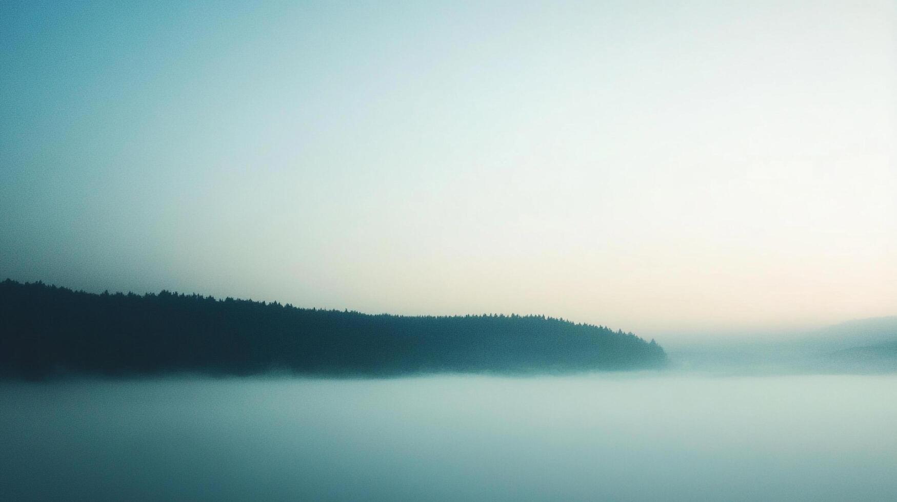 A tranquil landscape featuring a dense forest silhouette emerging from a layer of ethereal mist under a soft, gradient sky. photo