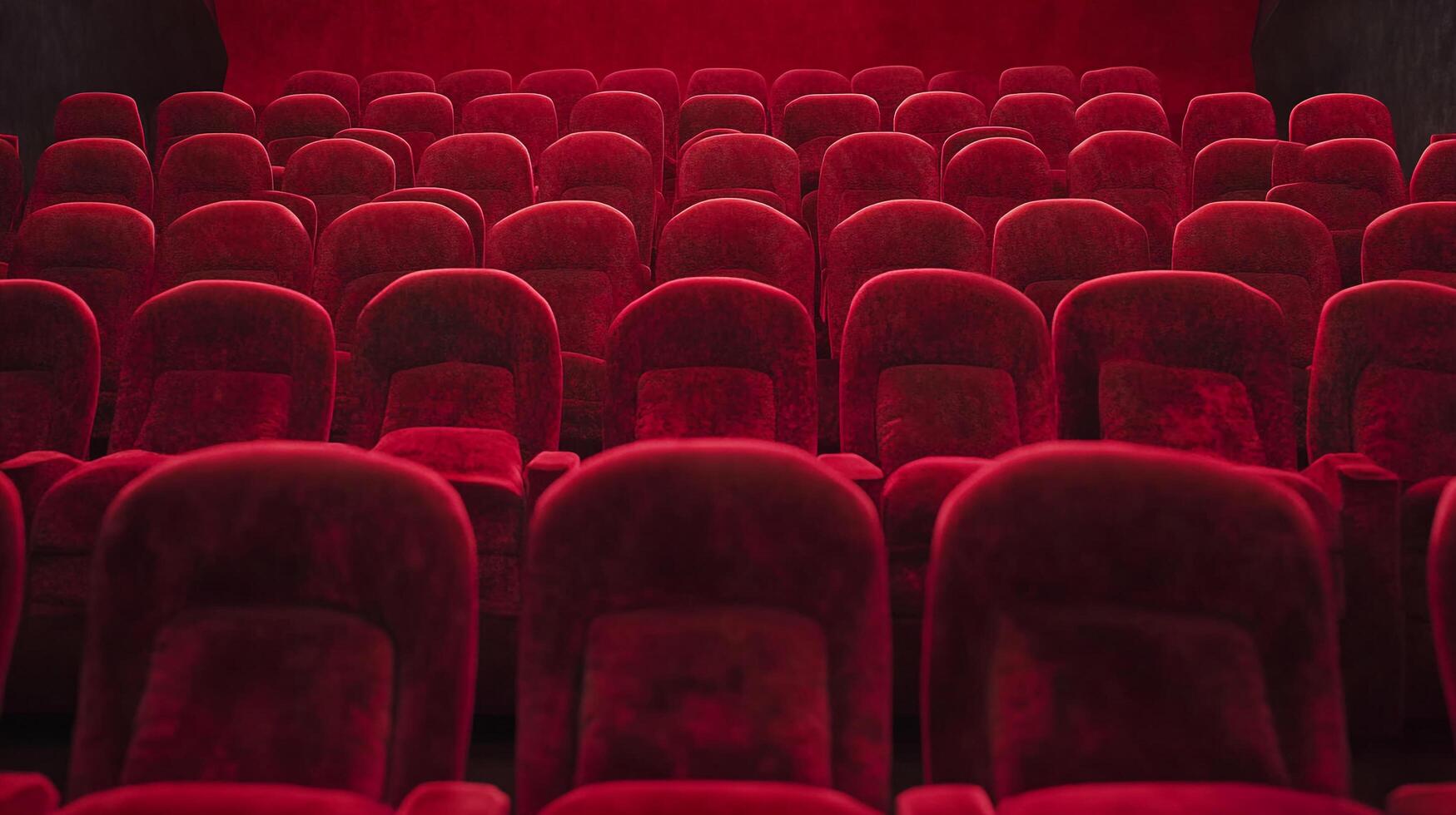 Rows of empty red plush seats facing the stage in a dark theatre are ready for the show. The plush seating is neatly arranged. photo