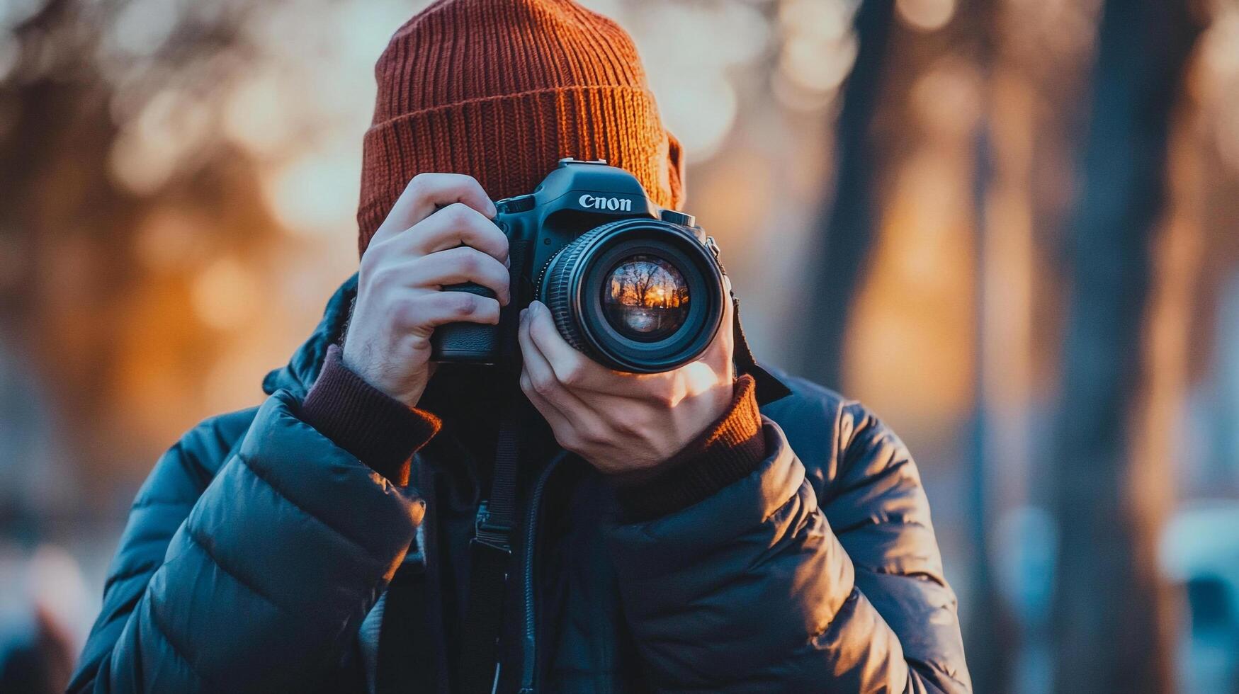 Photographer with camera captures a scene through the lens, wearing warm clothing on a cold day, reflecting light in the lens. photo