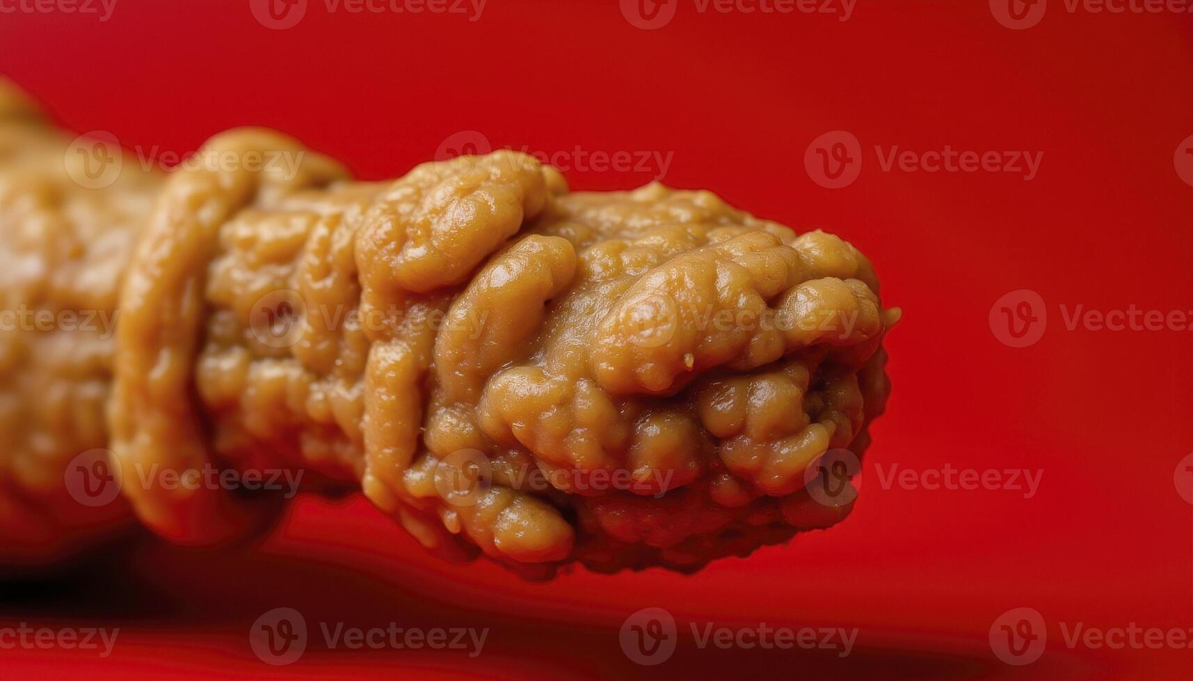Close-up Photography of a Textured Peanut Butter Treat on a Red Background, Showcasing Irregular Surface Details and Rich Color Contrast, Highlighting Unique Food Textures, Suitable for Culinary photo