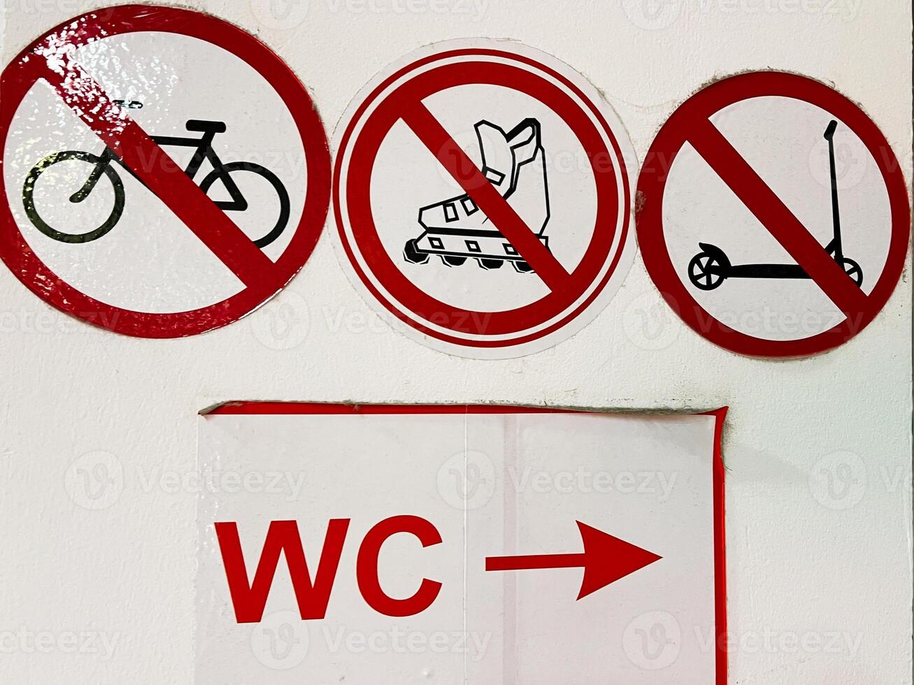 Prohibition signs for bicycles, roller boots, scooters, near a restroom direction sign photo