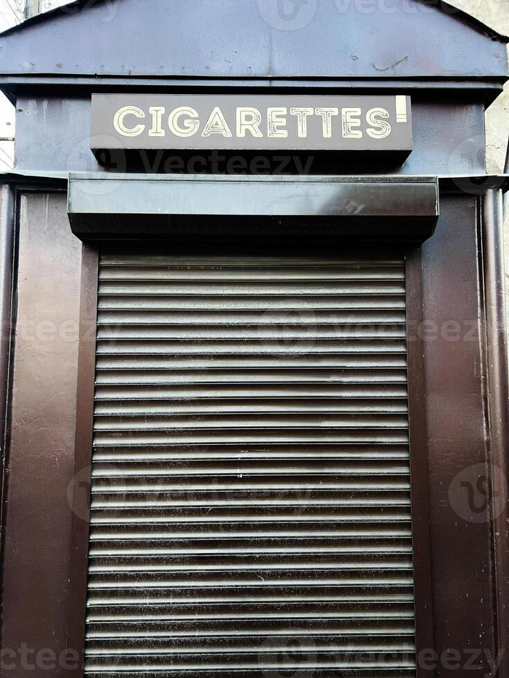 Closed rolling shutter kiosk with cigarettes sign on top viewed closely. photo