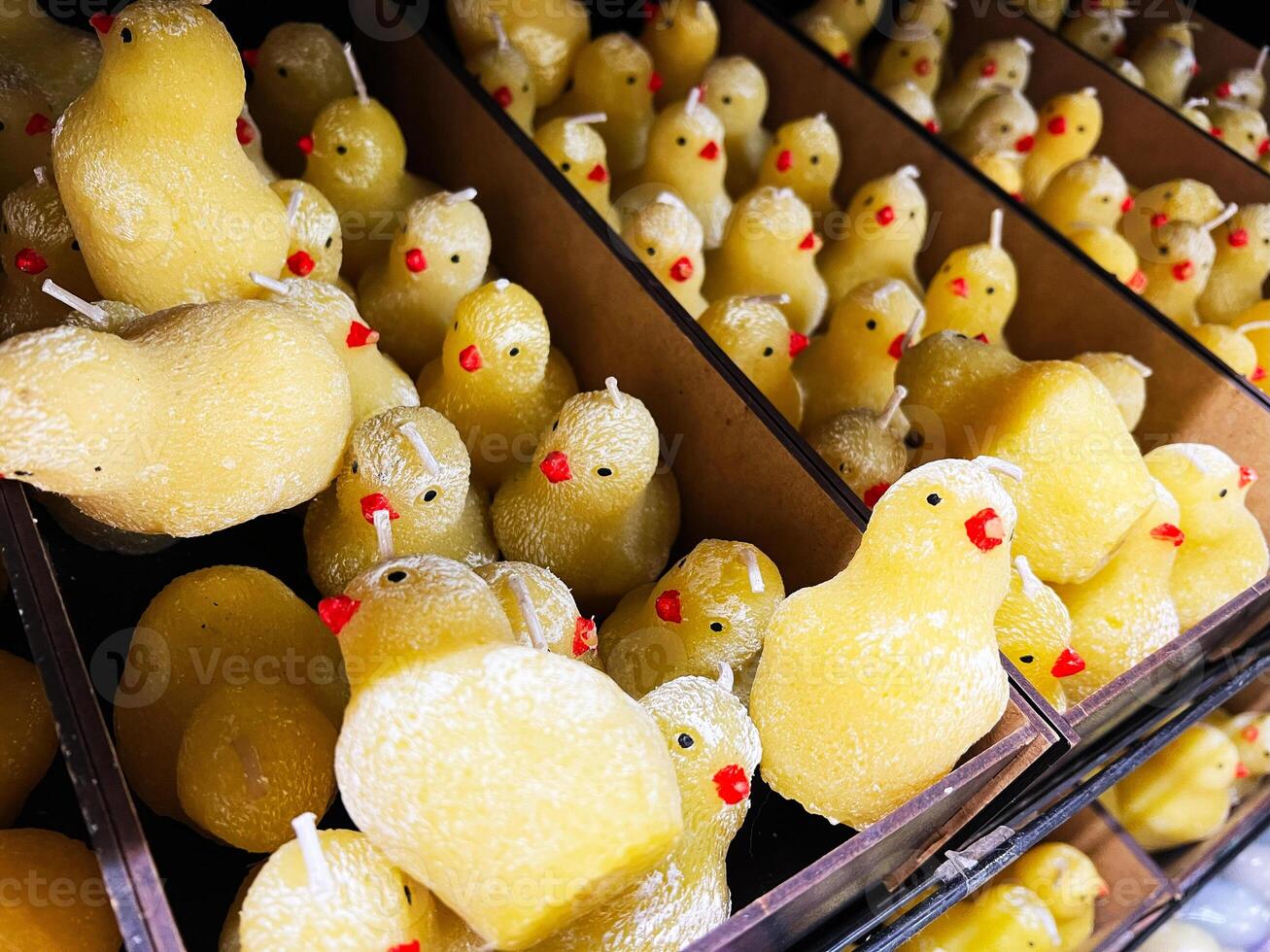 Yellow chick candles aligned in display boxes with close-up details photo