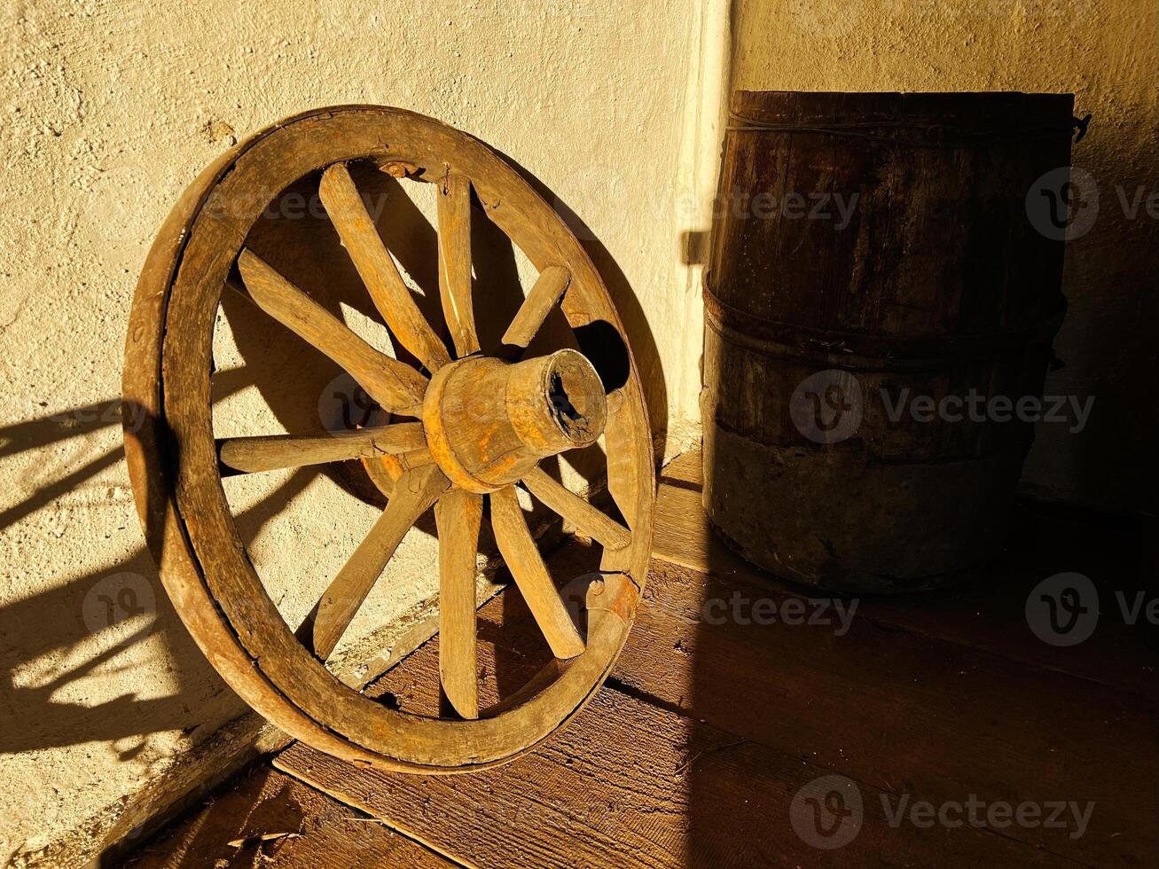 Rustic wooden wagon wheel and old wooden barrel in warm sunlight photo
