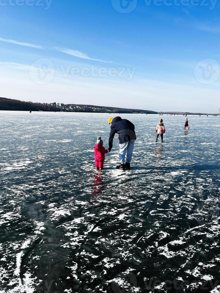 Family enjoying a fun day outdoors on a frozen lake under clear skies photo