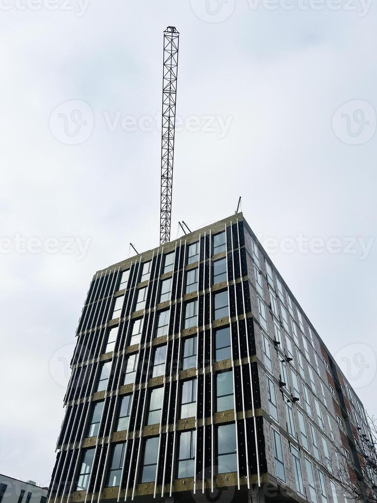 Modern high-rise building under construction with metallic framework against cloudy sky photo