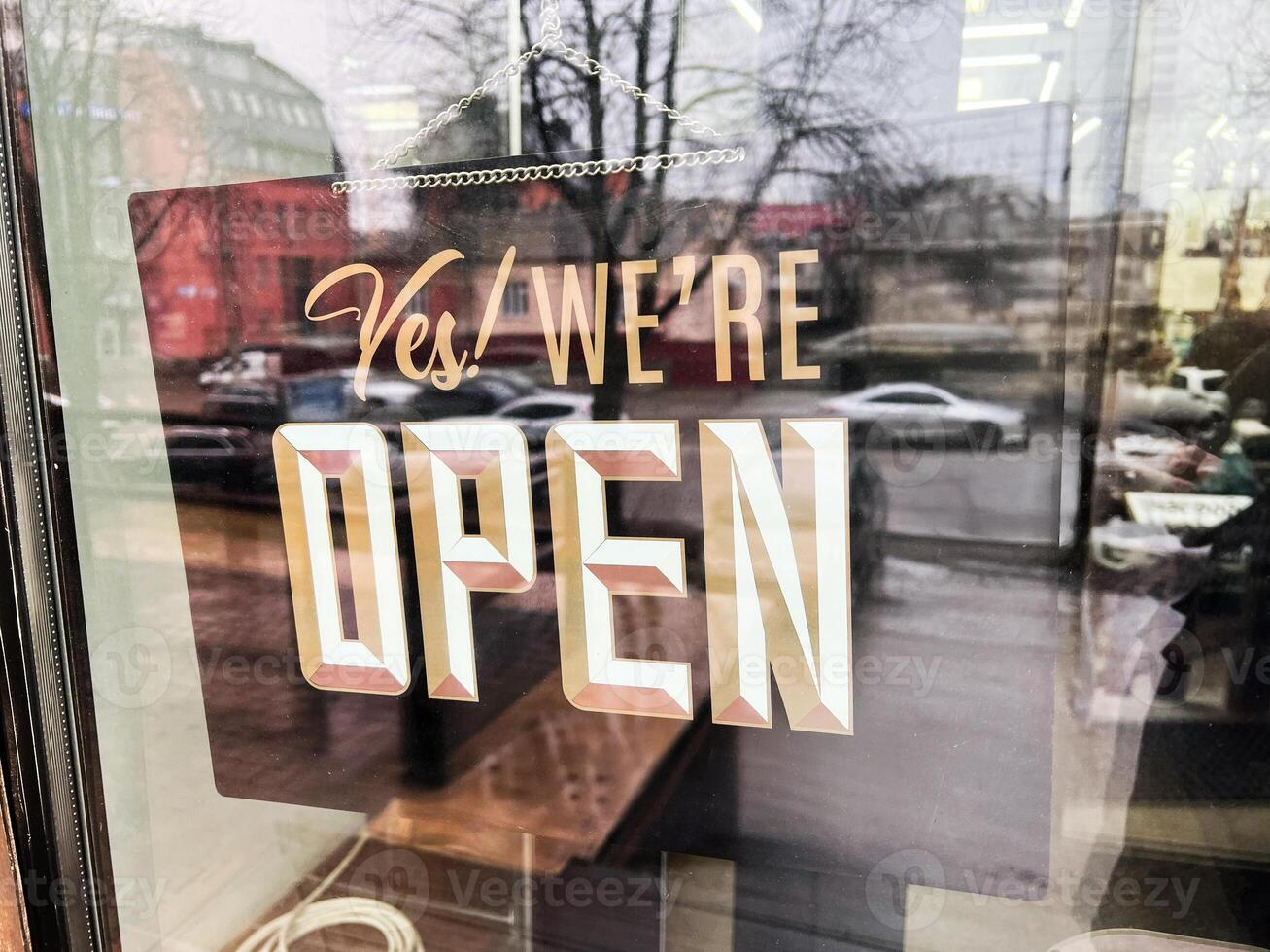 Open sign on a shop window with reflections of a street behind photo