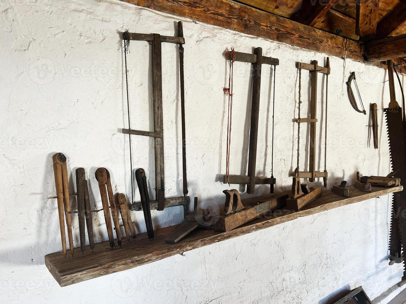 Set of antique woodworking tools stored on a wall-mounted wooden shelf photo