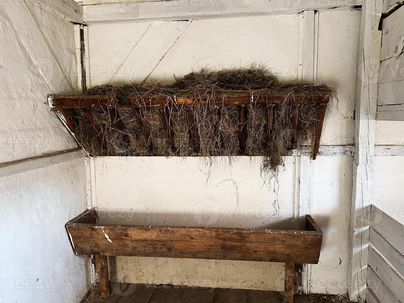 Traditional farm stable interior with wooden hay rack and feeding trough design photo
