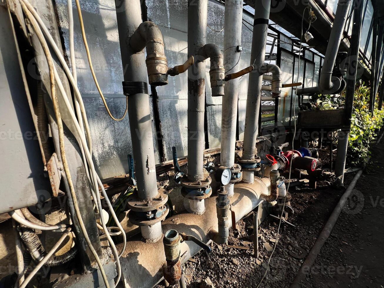 Industrial piping system with valves and gauges inside a greenhouse environment photo