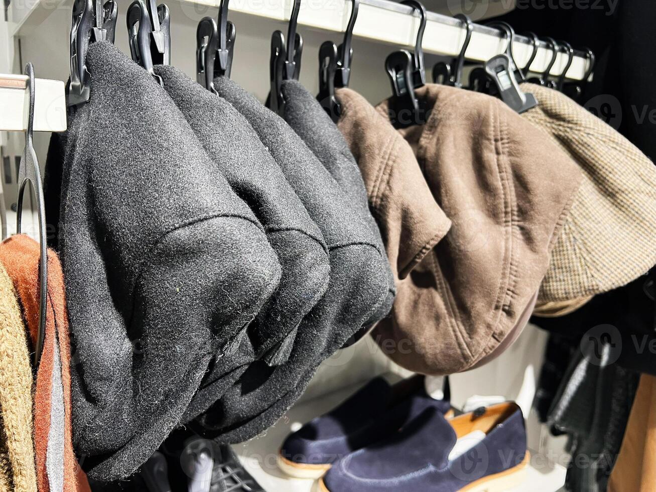 A collection of stylish hats displayed on hooks with shoes nearby photo